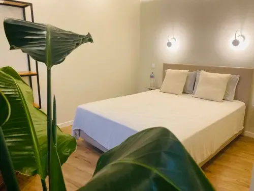 Modern bedroom at Santa Cruz Historic Guest House in Lagos with a white bed, potted plants, pendant lights and wood flooring