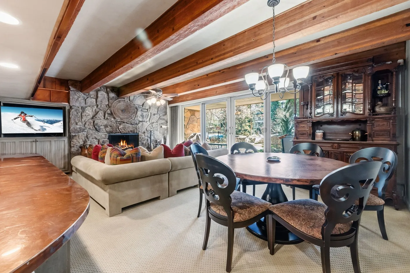 Sala de estar y comedor con vigas de madera a la vista y chimenea de piedra.