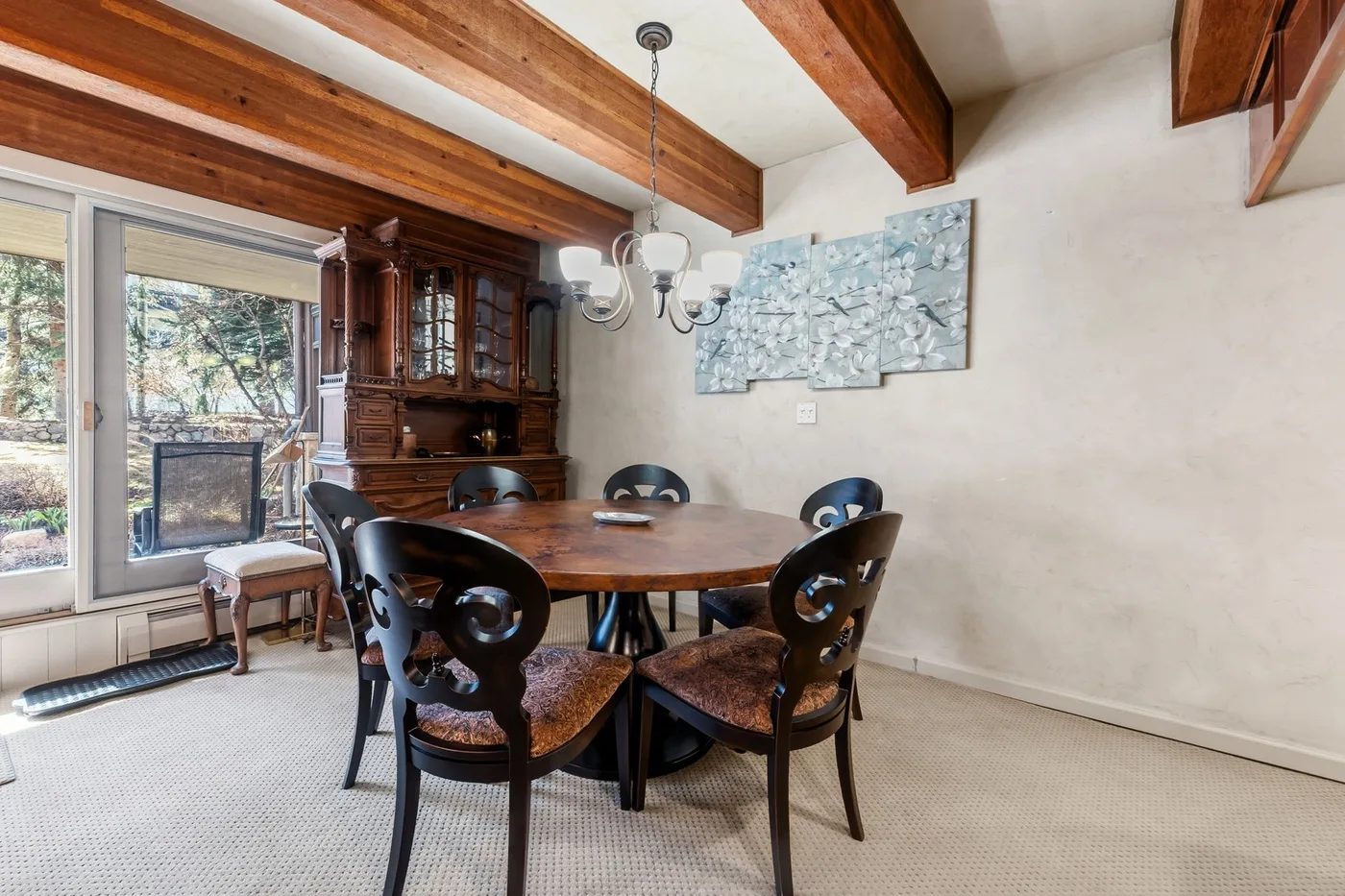 Comedor con una mesa de madera, asientos oscuros y ventanales.