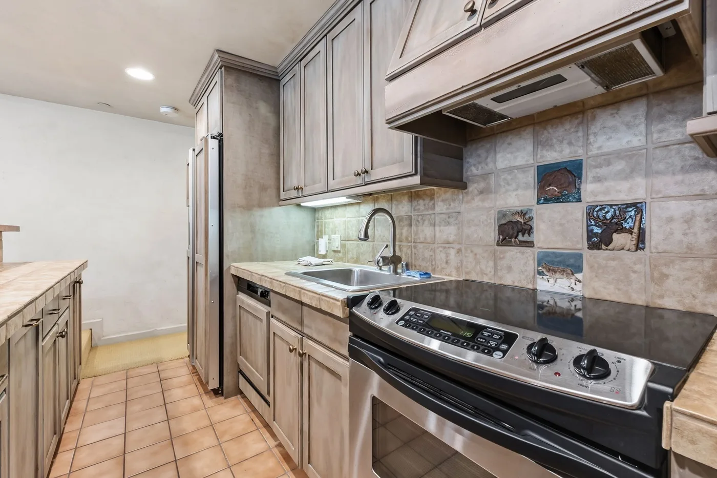 Una cocina con gabinetes de madera, un salpicadero de azulejos y una lavadora de carga frontal.