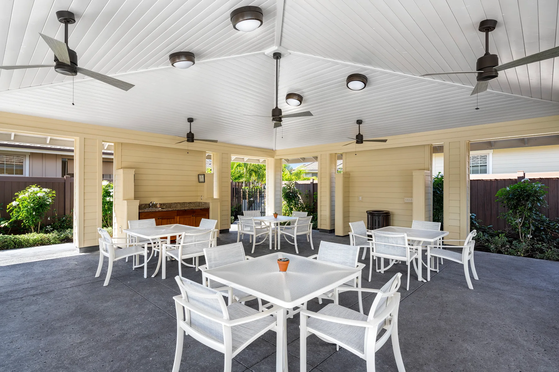 A covered outdoor dining area with white tables and seating.