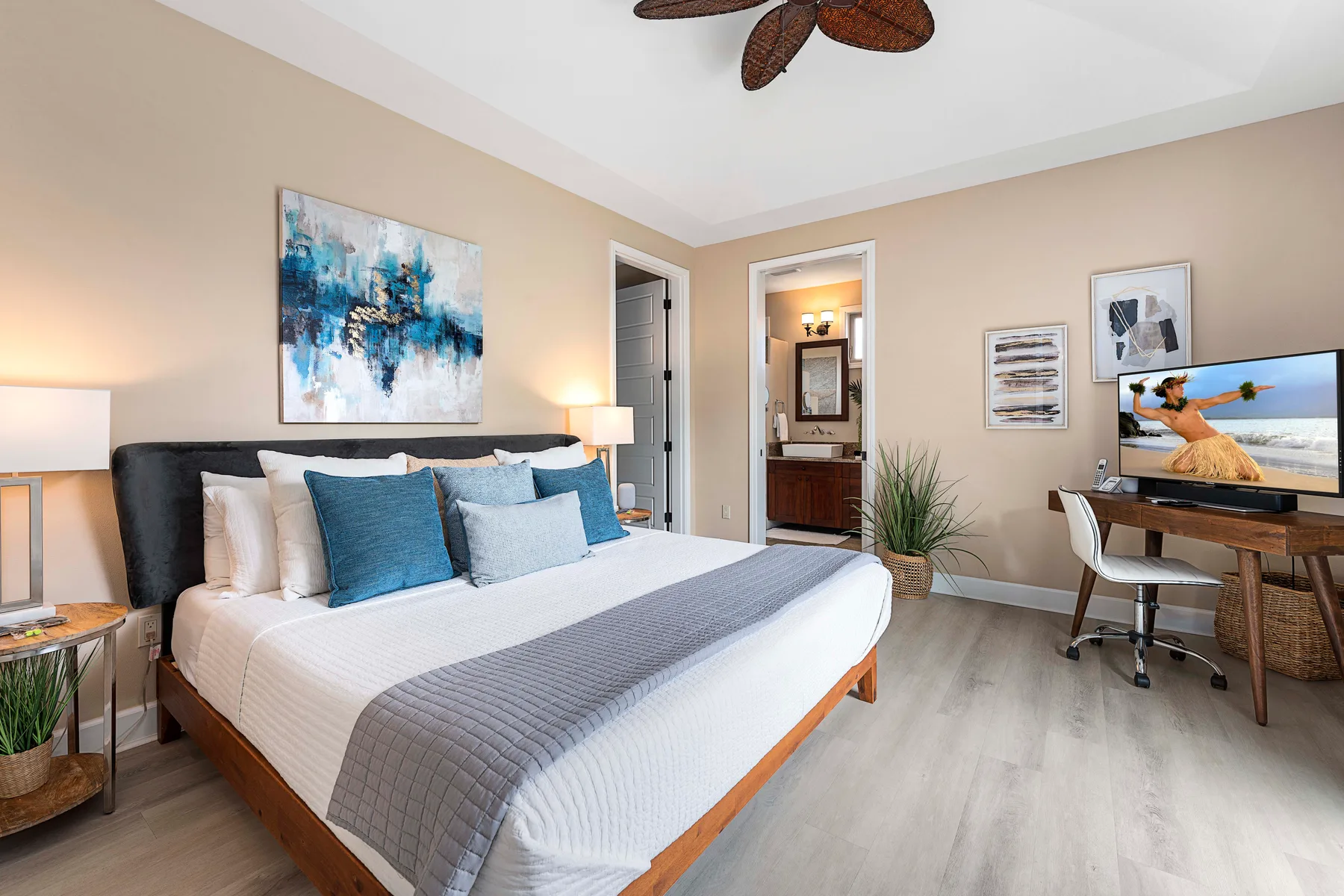 A bedroom with a large bed and a desk with a television.