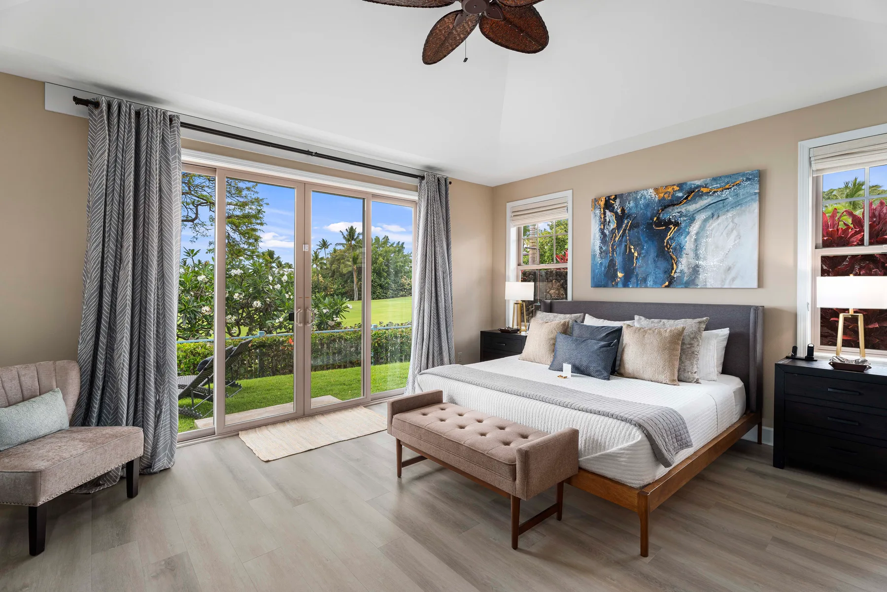 A bedroom with a large bed, bedside tables, and sliding glass doors overlooking greenery.