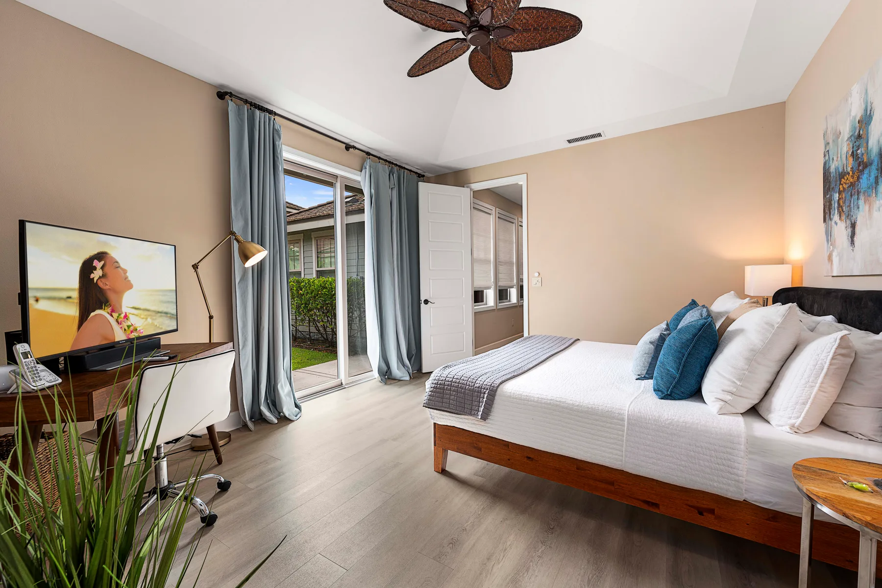 A bedroom with a bed, sliding glass doors, and a television.