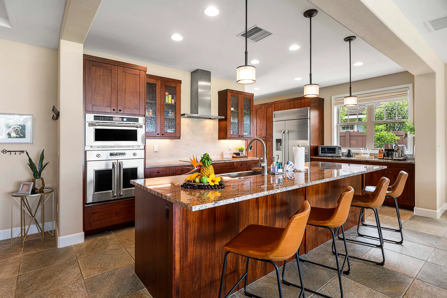 A spacious kitchen with a central island, pendant lights, and wood cabinetry.