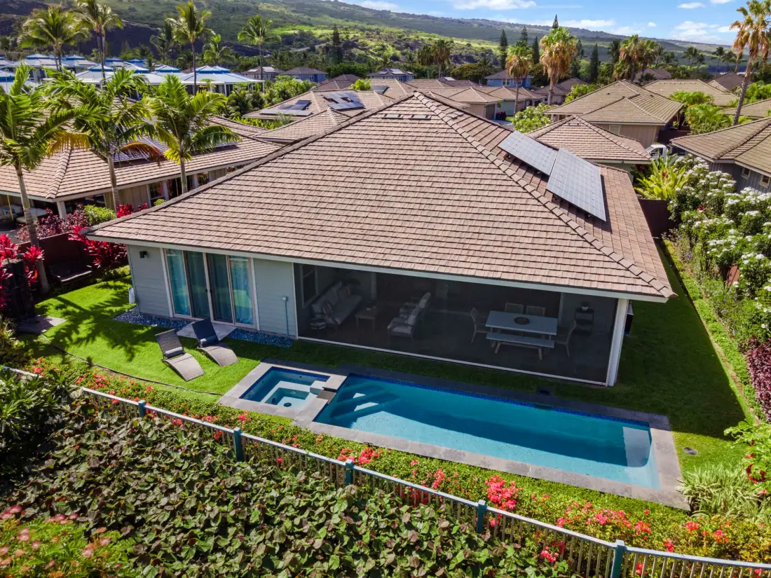 A landscaped home with a swimming pool and patio seating beside the house.