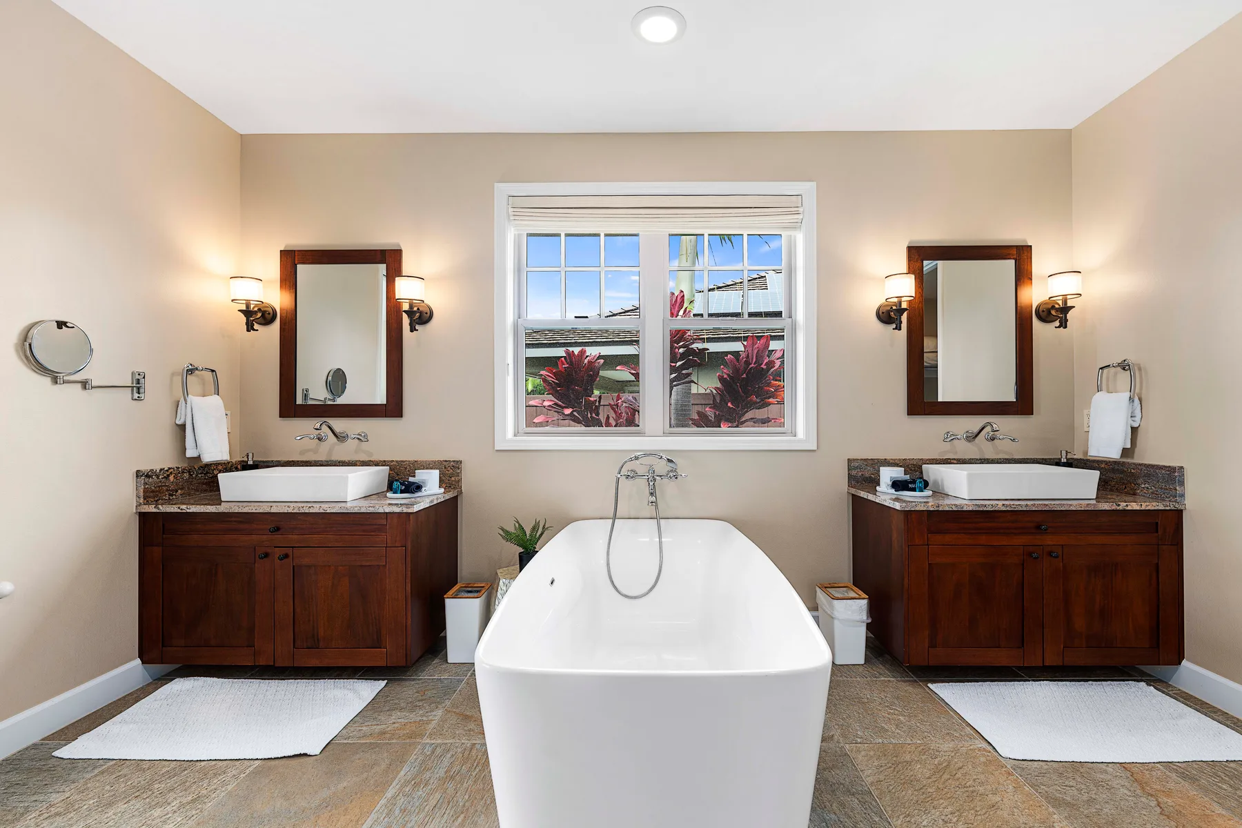 A bathroom with a freestanding bathtub between two dark wood vanities.