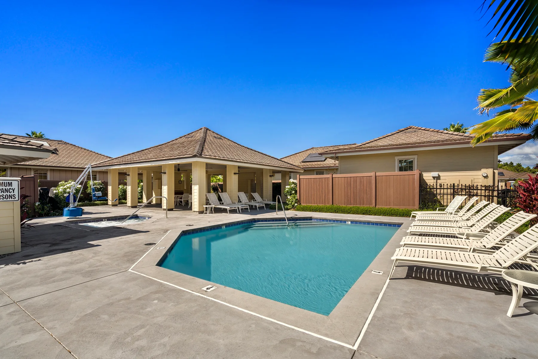 Outdoor pool area with lounge seating beside a covered patio.