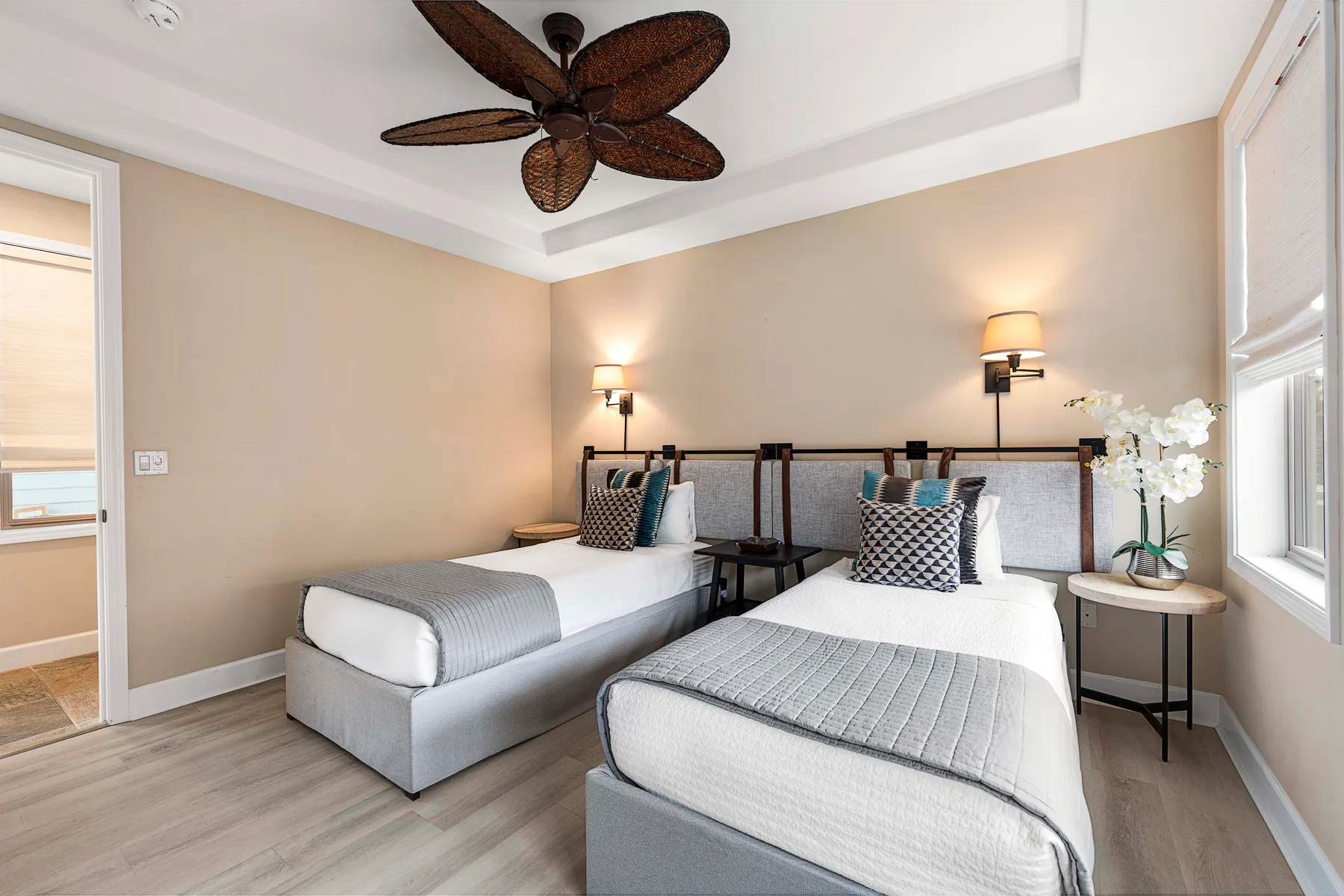 A bedroom with two beds, bedside tables, and a ceiling fan.
