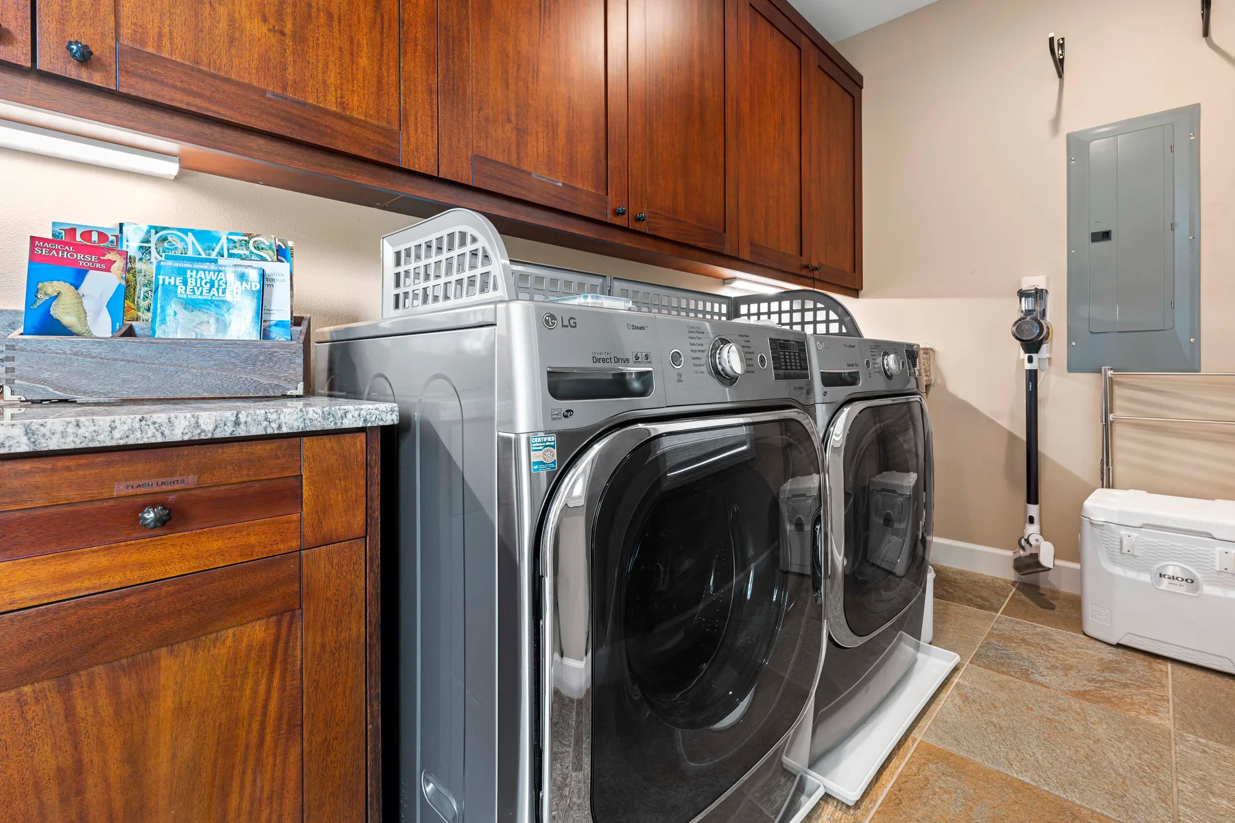 A laundry room with front-loading washing machines beneath wooden cabinets.