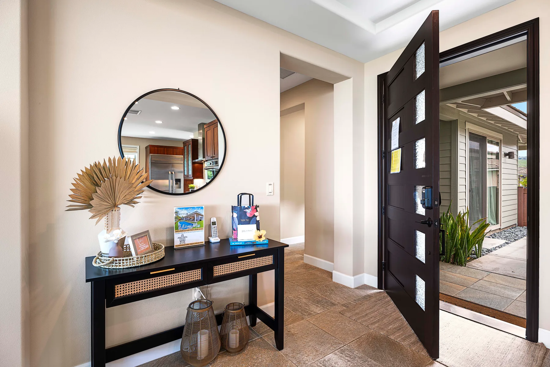 An entryway with a dark console table beneath a round wall mirror.