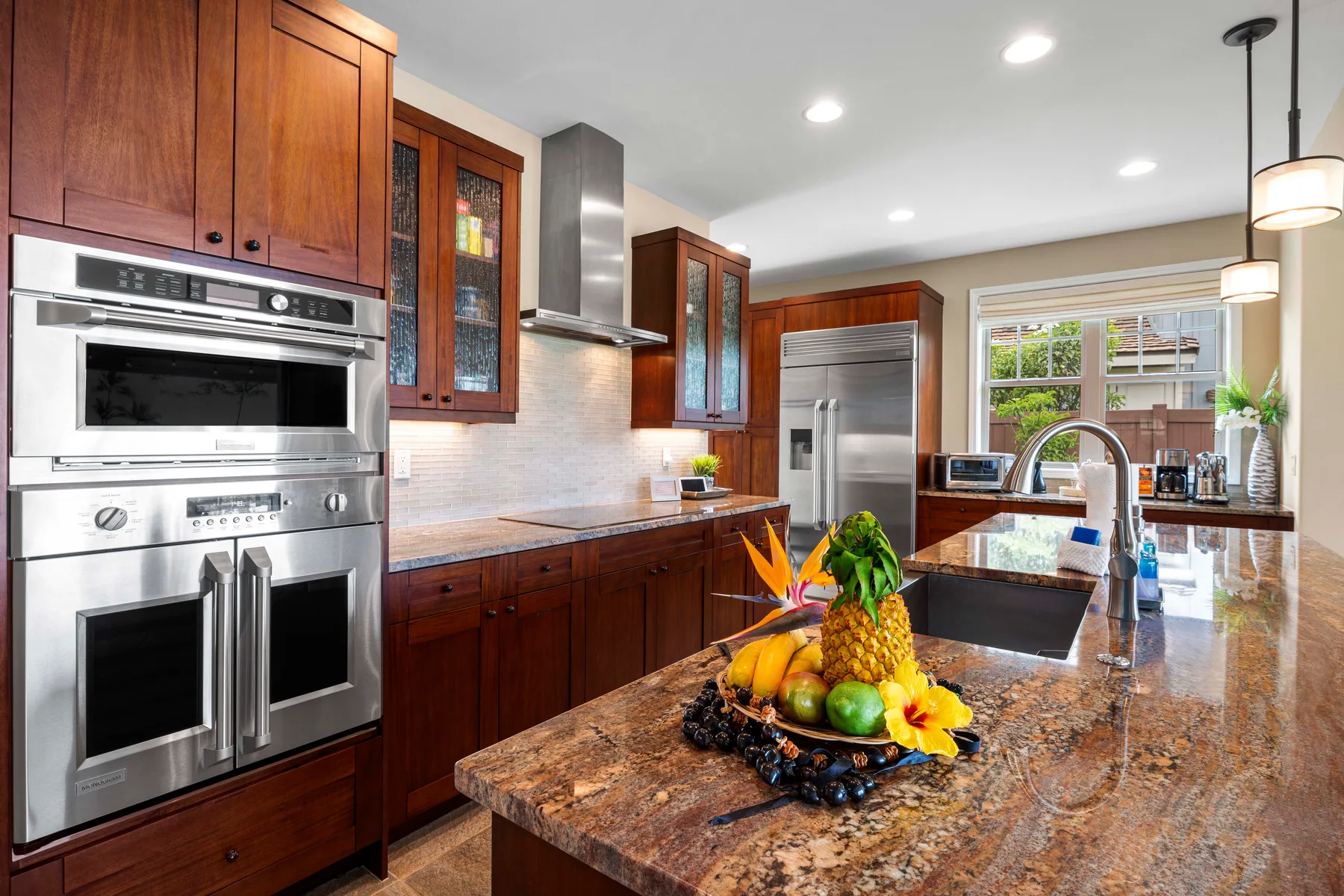 A kitchen with dark wood cabinetry, stainless steel appliances, and a large island.