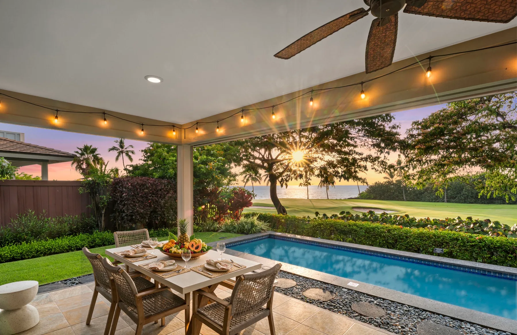 A covered outdoor dining area overlooks a swimming pool and a tree-lined view.