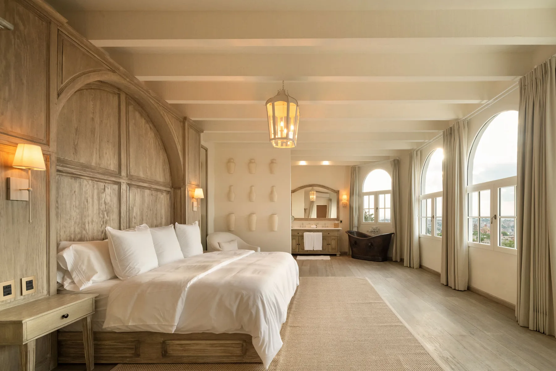 Un dormitorio con una cama grande y altas ventanas arqueadas.