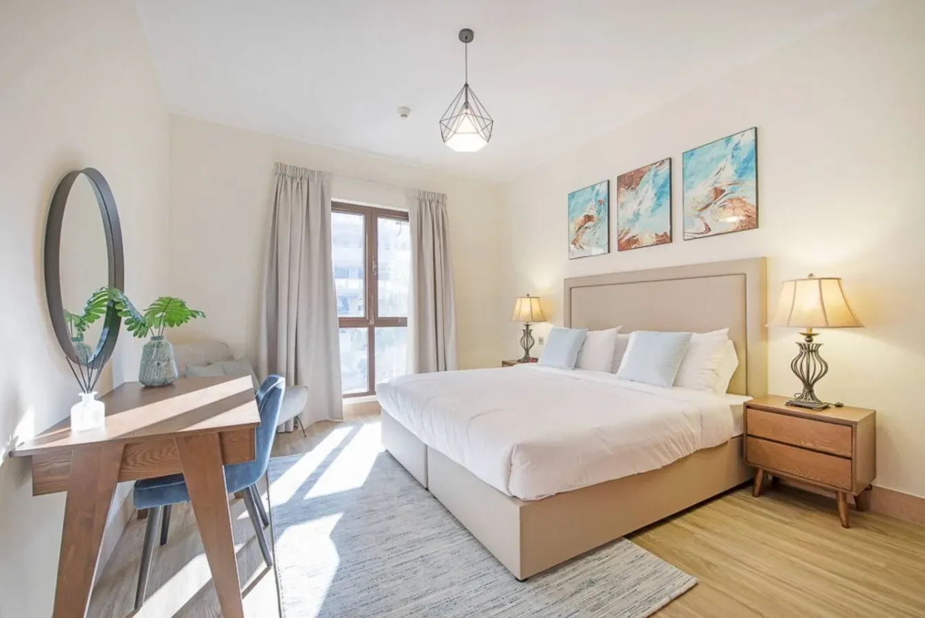 A bright bedroom with a bed, bedside tables, and a desk by the window.