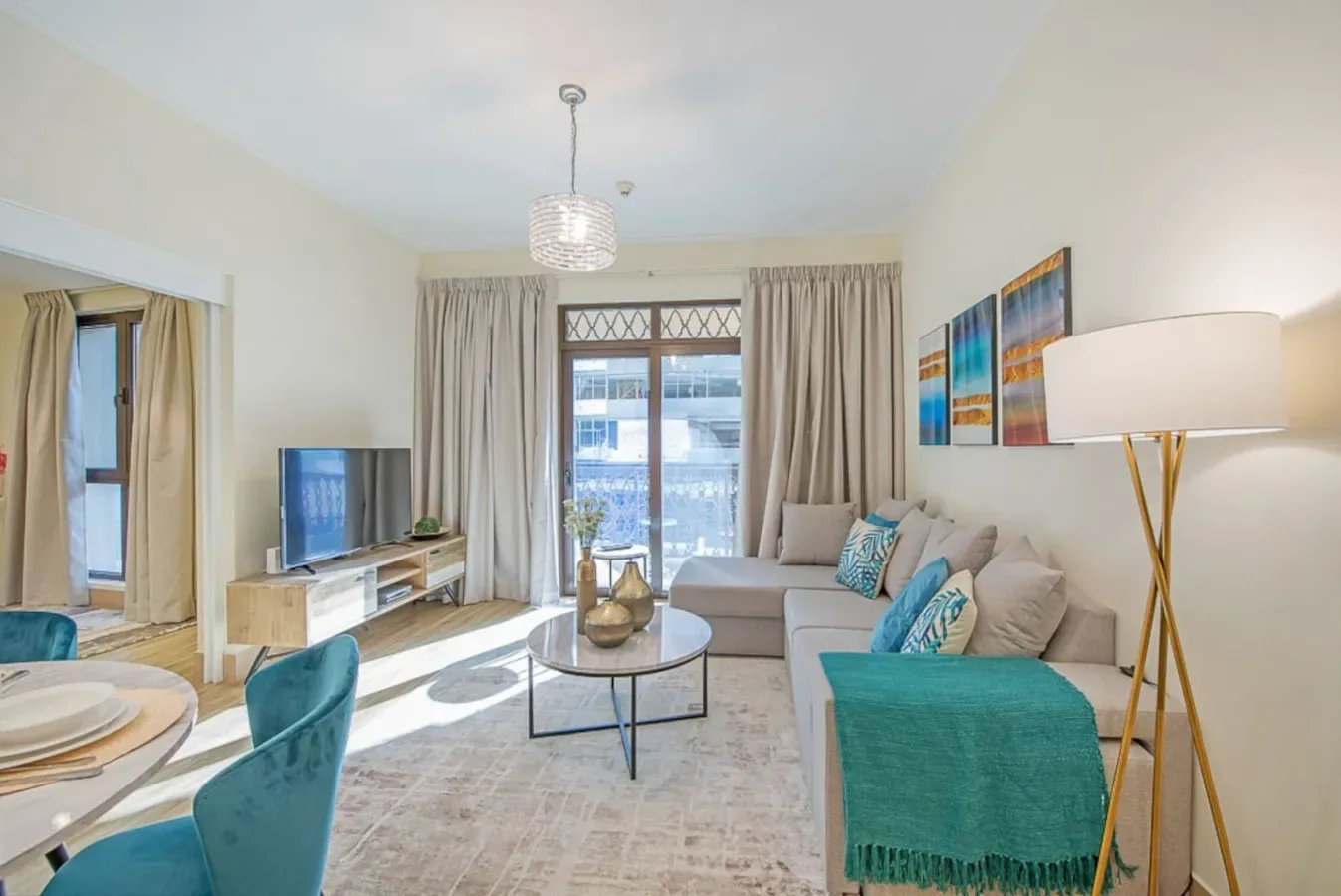 A bright living room with a sofa, coffee table, and large curtained windows.