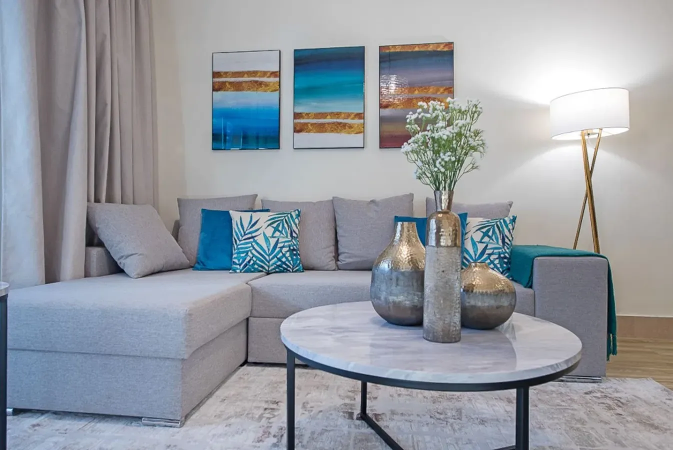 A living room with a gray sectional and a round coffee table.