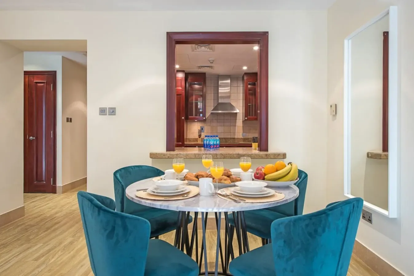 A dining area with teal seating around a table set with dishes and fruit.