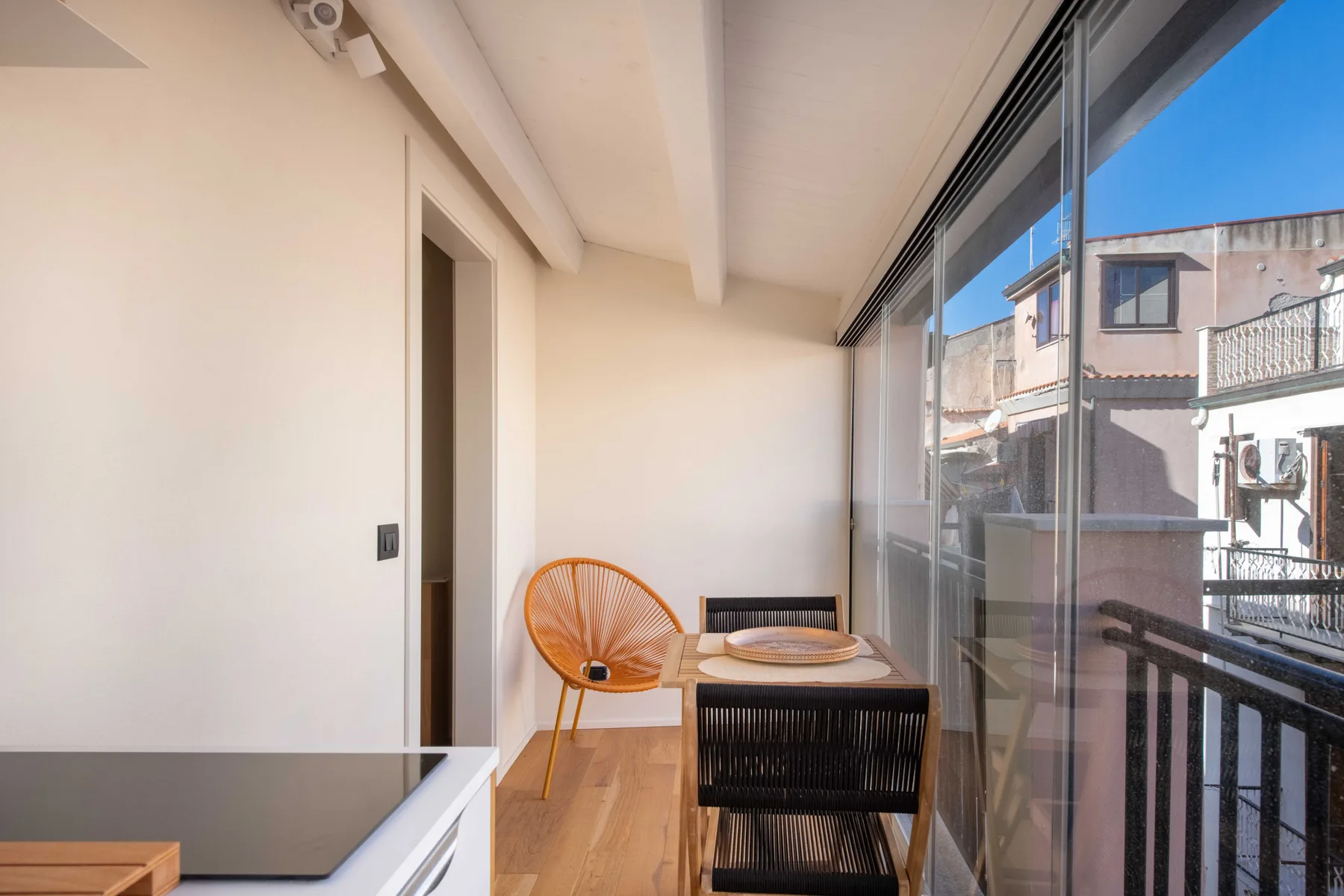 Una pequeña zona de comedor junto a ventanales, con una mesa y asientos.