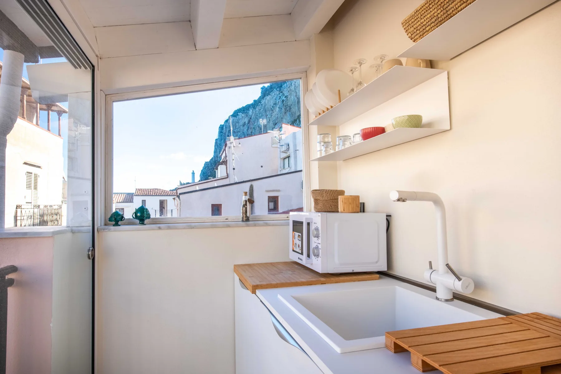 A bright kitchen with a sink, countertop, and a large window overlooking nearby buildings.
