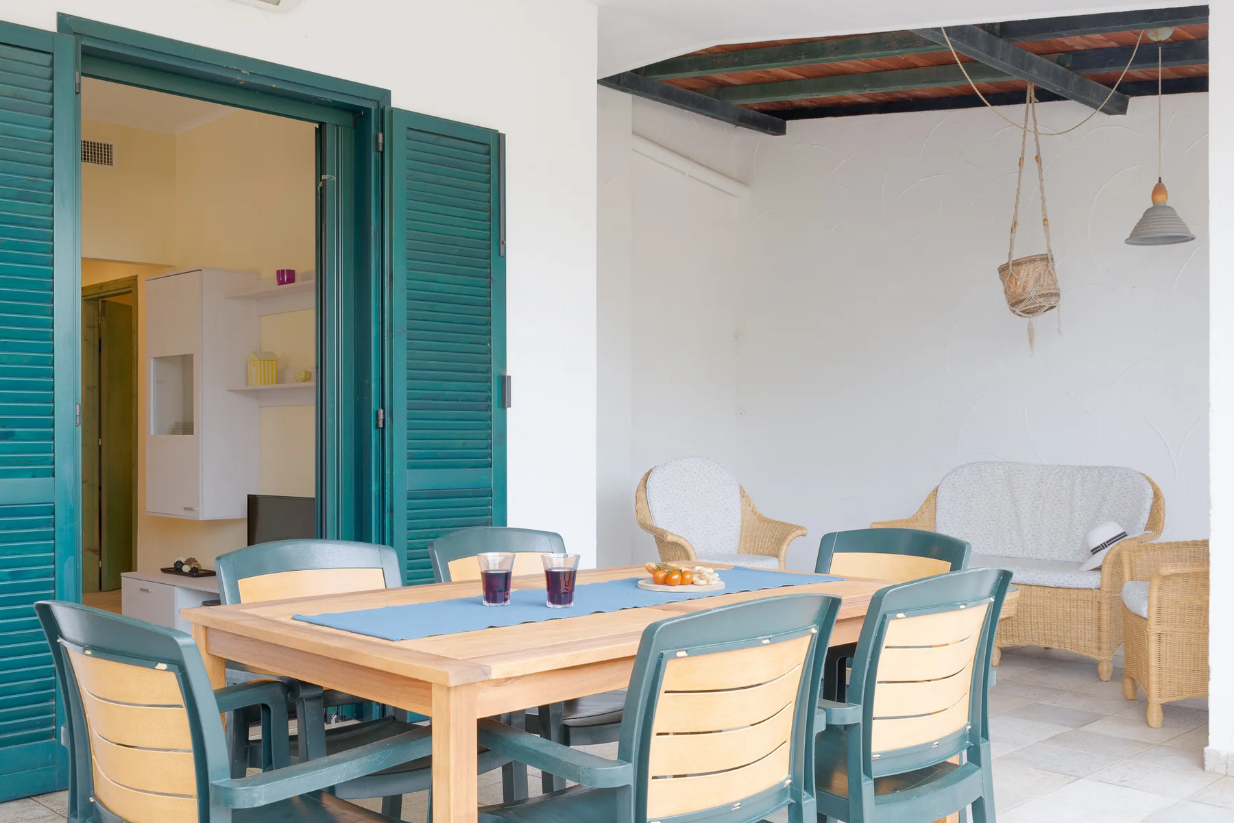 A dining area with a wooden table and teal seating beside an open kitchen.