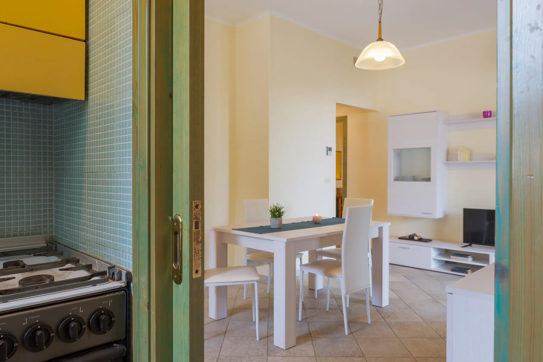 A dining area with a white table and chairs beside a compact kitchen.