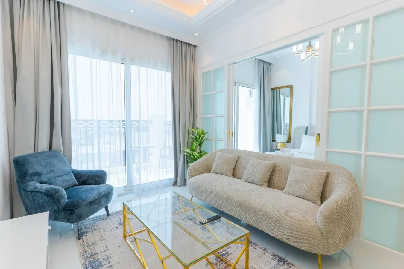 A bright living room with a beige sofa and glass coffee table.