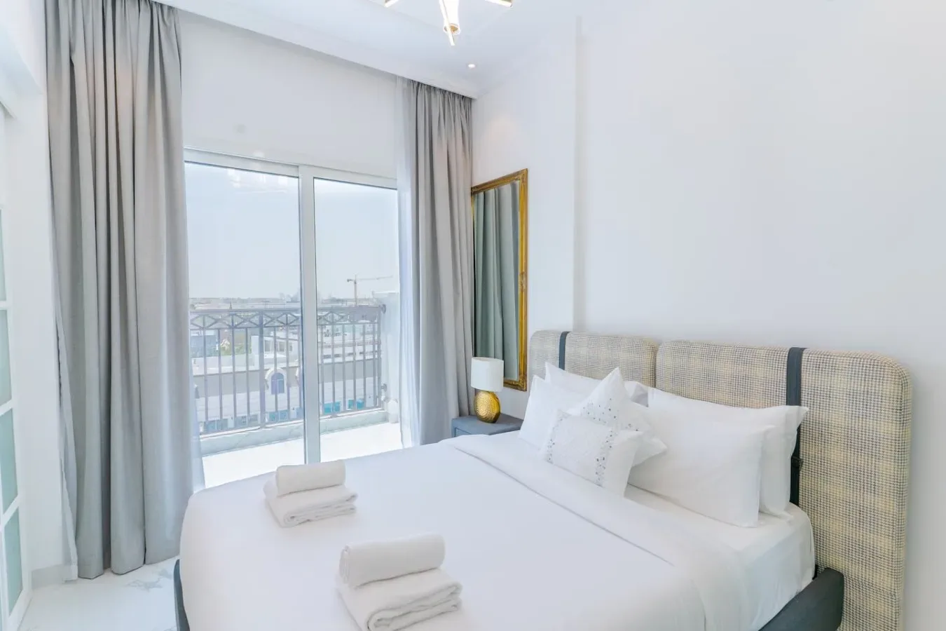 Un dormitorio luminoso con una cama bien arreglada junto a una ventana amplia con cortinas.