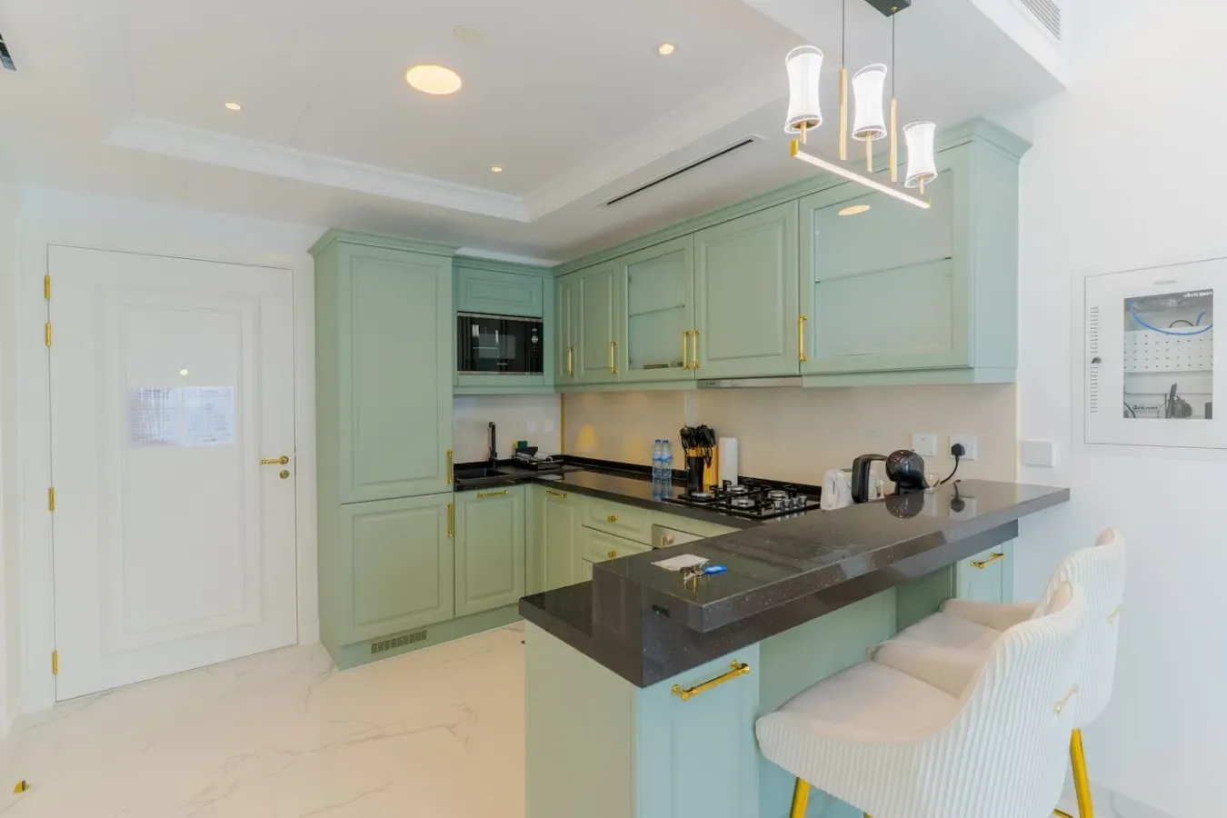 A mint-green kitchen with a dark island and light-colored seating.