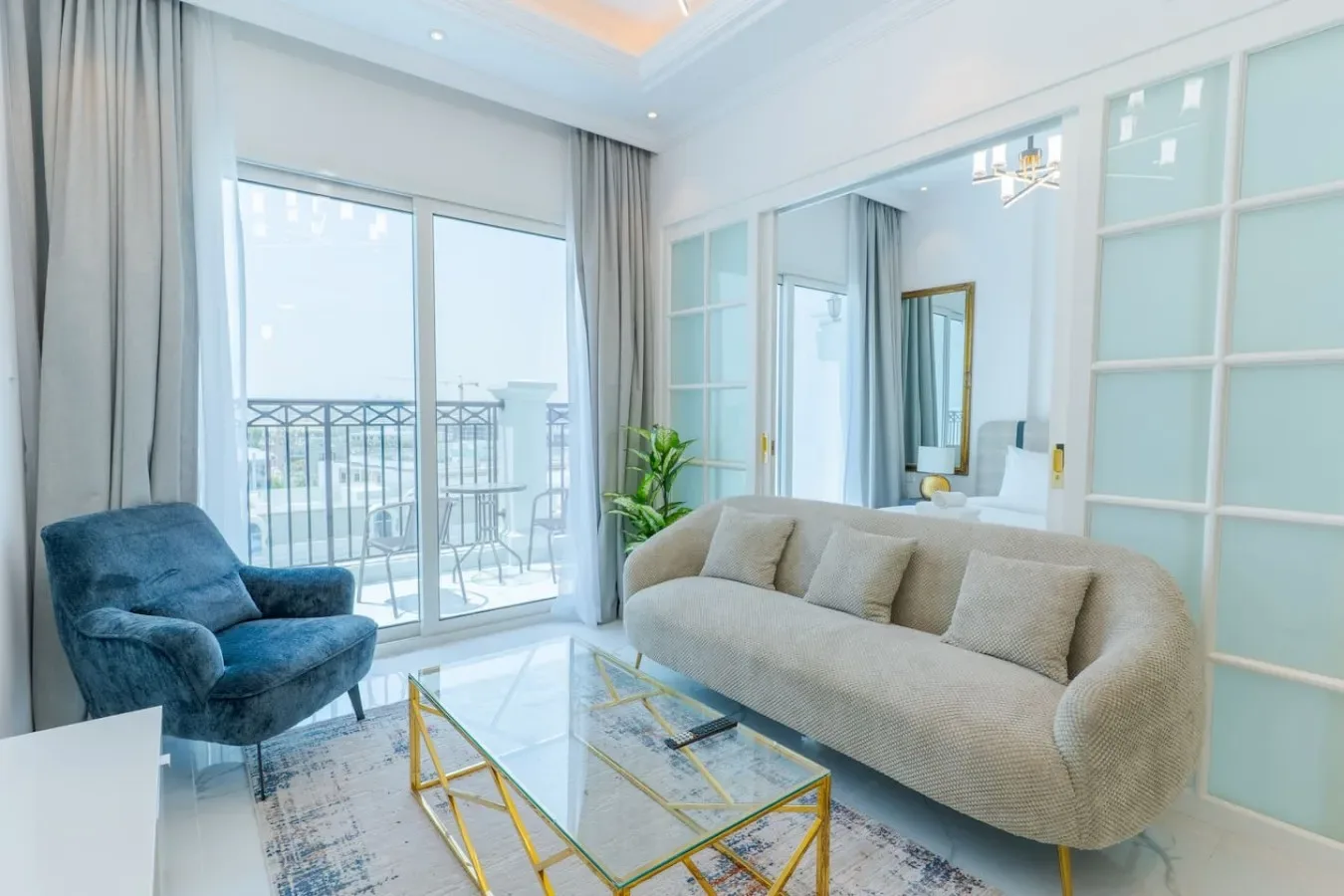 A bright living room with a beige sofa and glass doors opening onto a balcony.