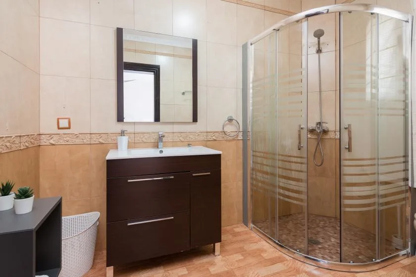 A tiled bathroom with a vanity and a curved glass shower.