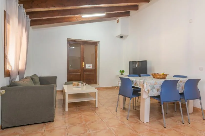 A living and dining area with seating, a table, and wooden ceiling beams.