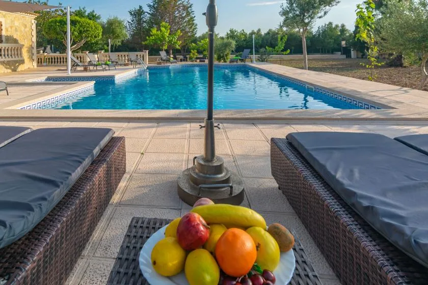 A swimming pool bordered by paved seating areas and greenery.