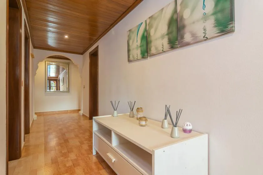 A hallway with a console table and framed abstract artwork on the wall.