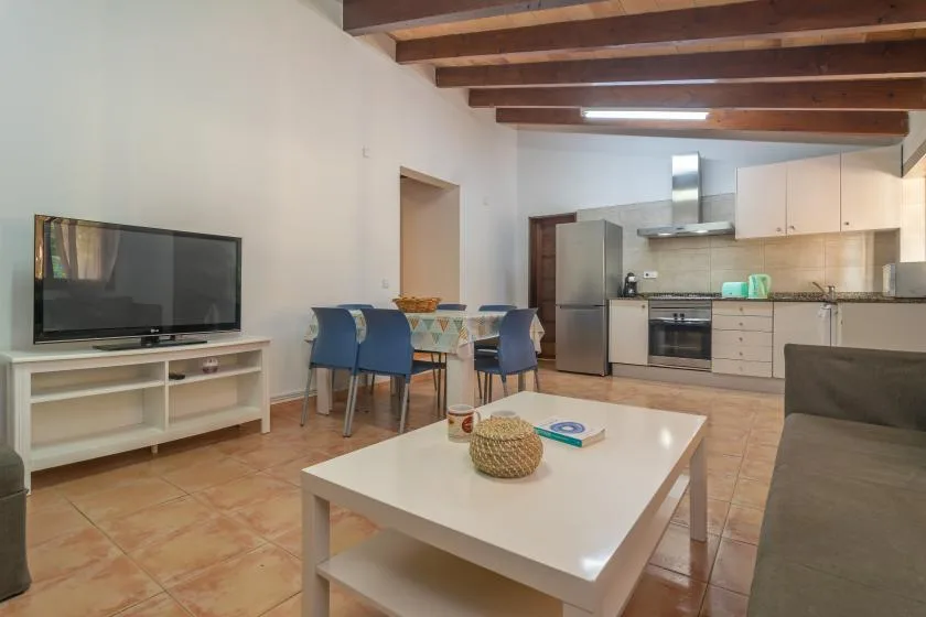 An open-plan living and dining area with a kitchen and a low white table.