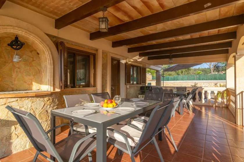 A covered outdoor dining area with a long table and patio seating.