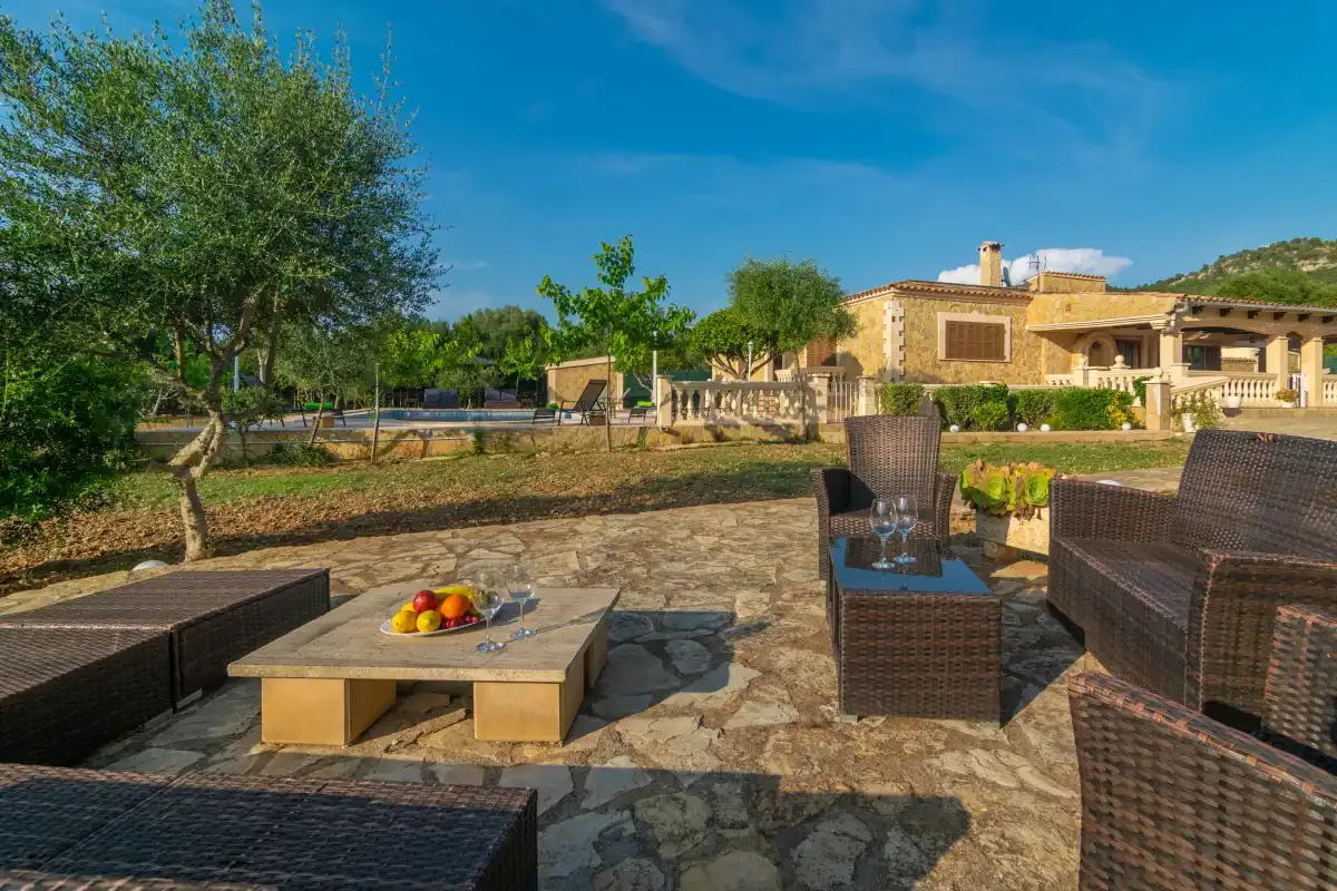 A sunny stone patio with dark wicker seating and a low table.