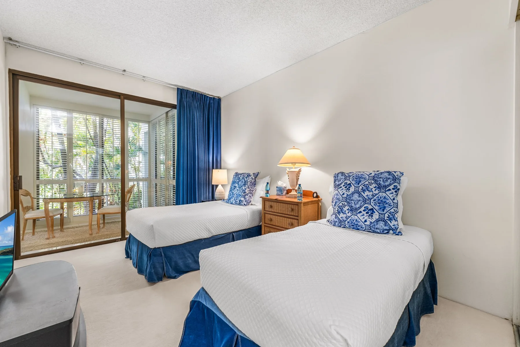 A bedroom with two beds and a sliding glass door opening onto a balcony.