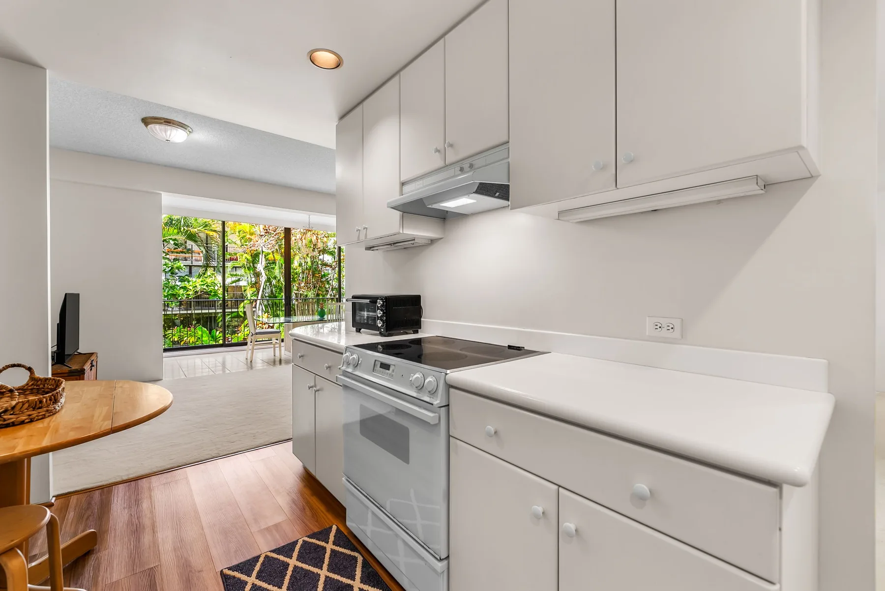 A bright kitchen with white cabinets, a stove, and a counter.