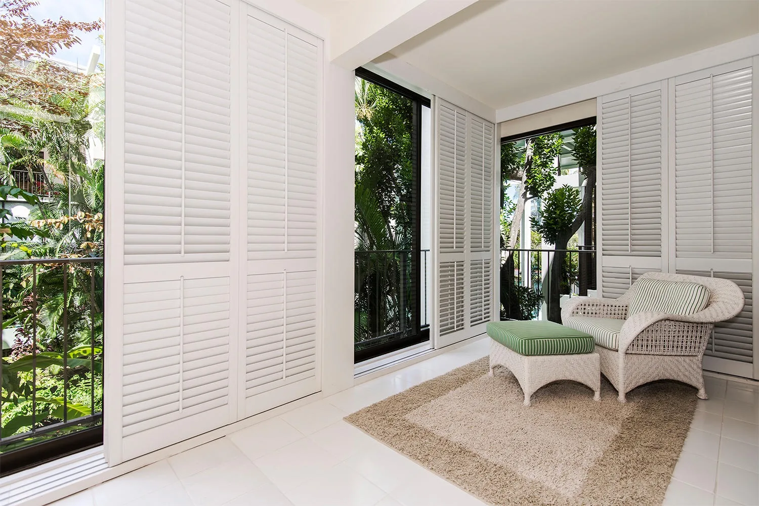 A bright sitting area with white louvered shutters and cushioned seating.