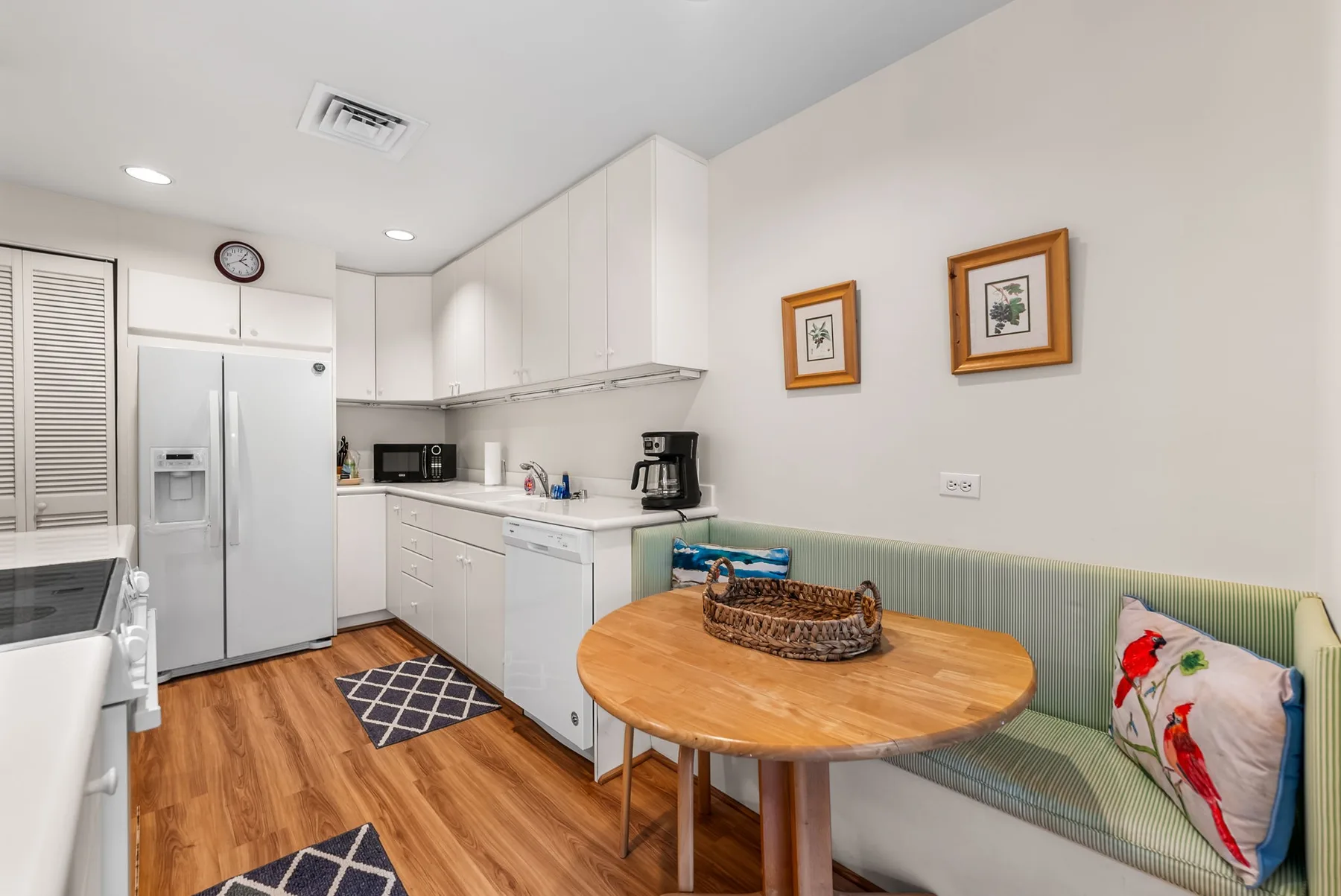 A bright kitchen and dining area with white cabinets and a round wooden table.