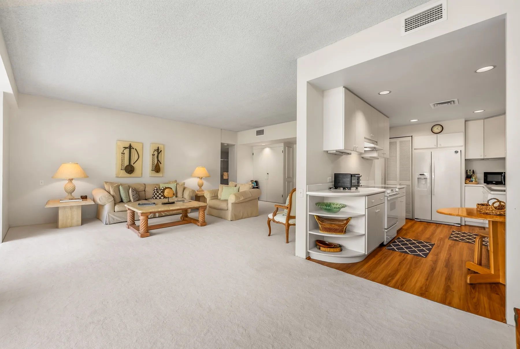 An open living room and kitchen with seating and wood flooring.