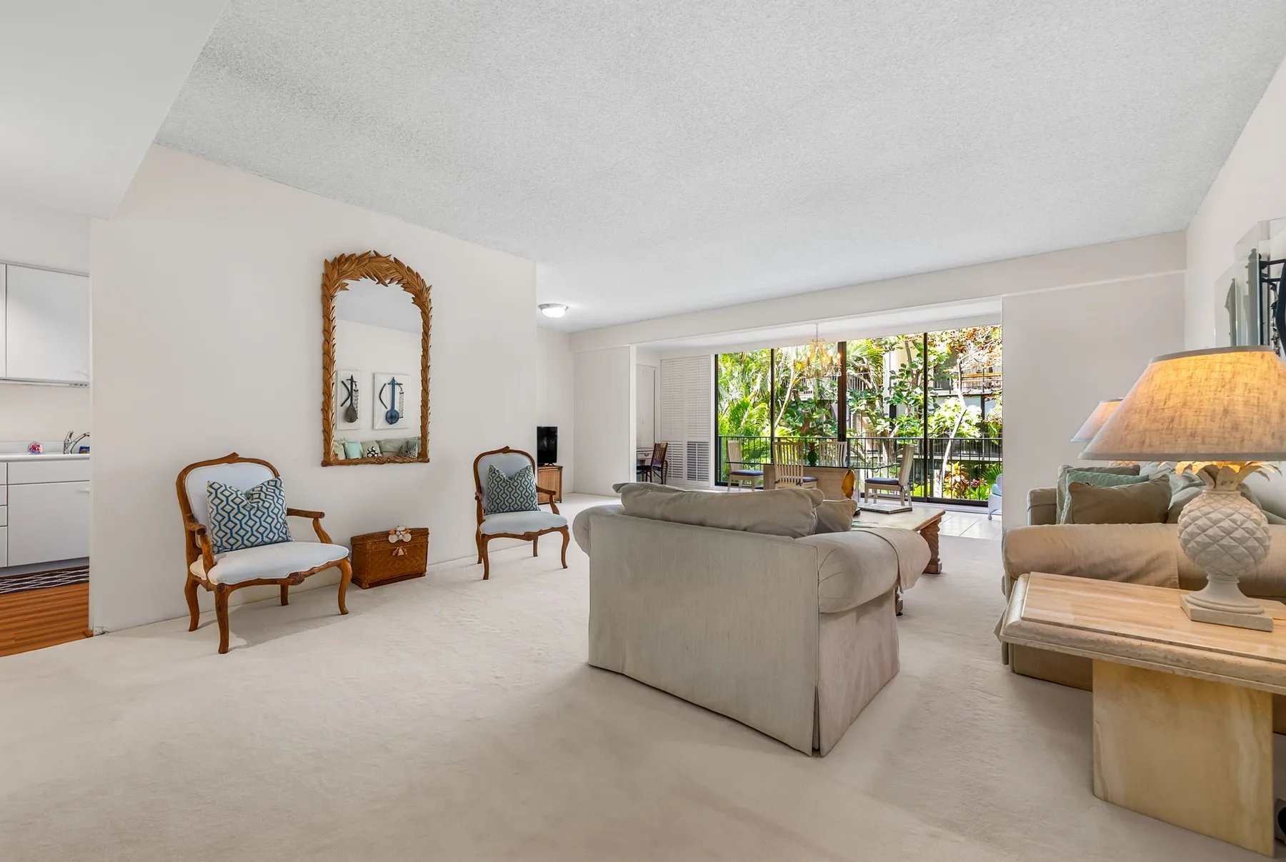 A spacious living room with seating arranged around a central sofa and large windows.