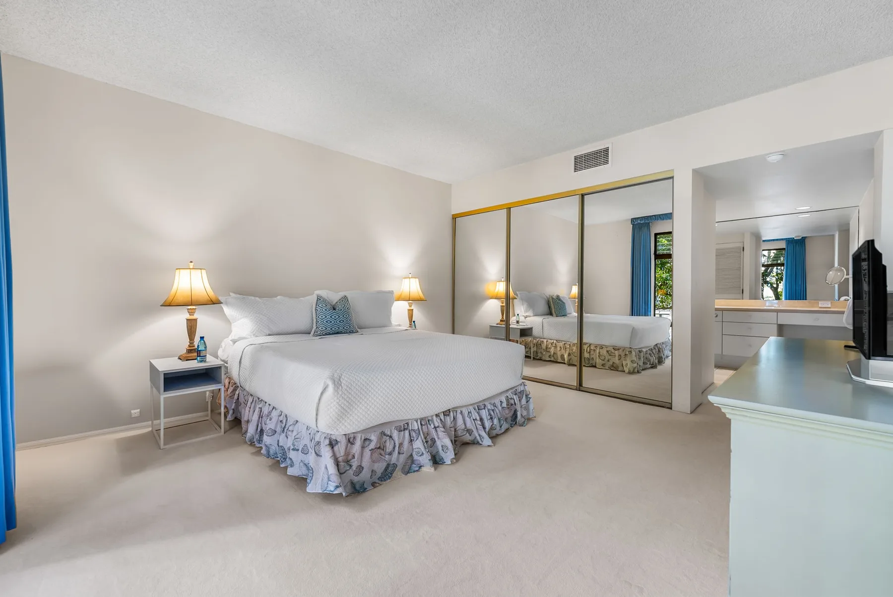 A bedroom with a large bed, bedside tables, and a wall mirror.
