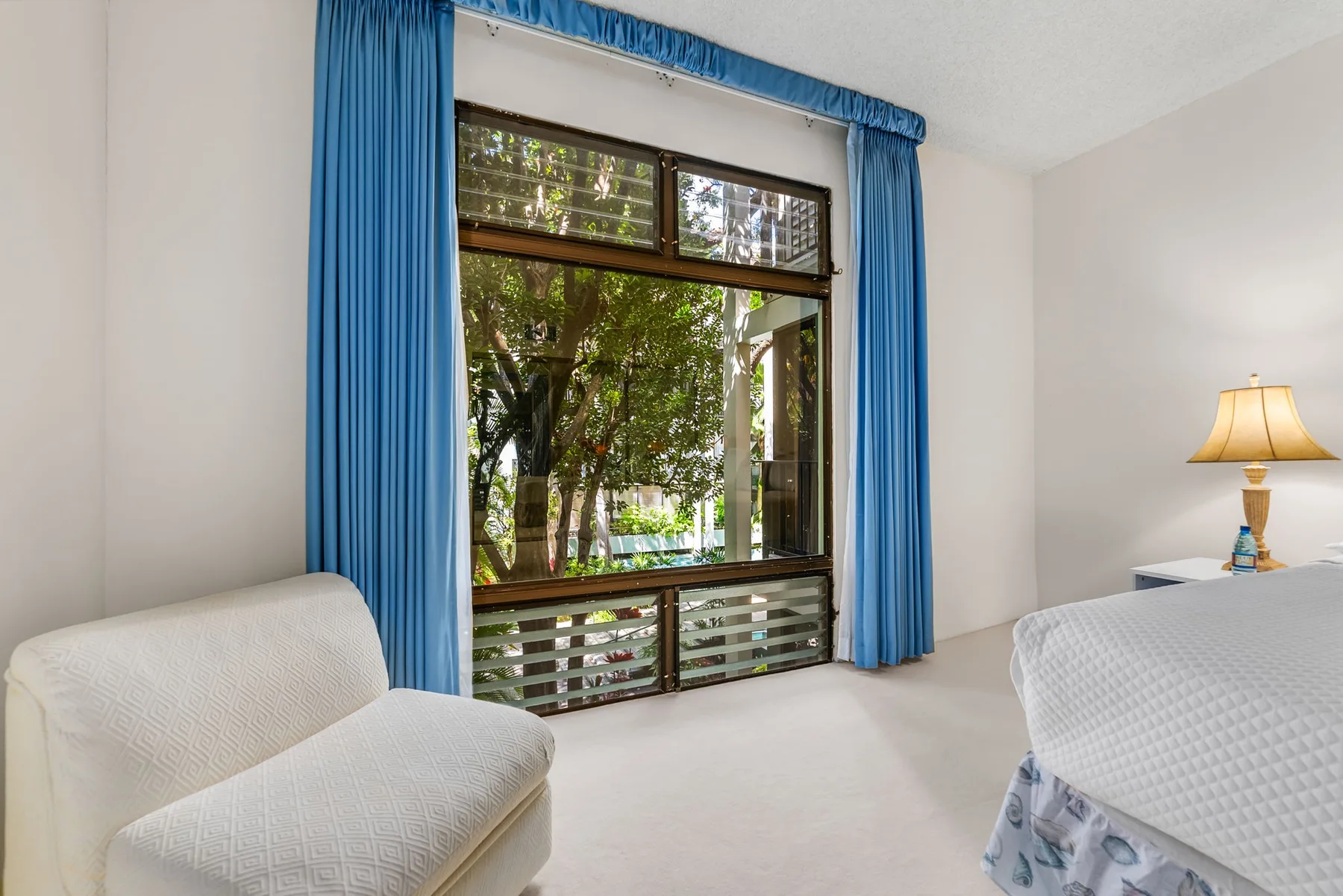 A bedroom with blue curtains framing a large window.