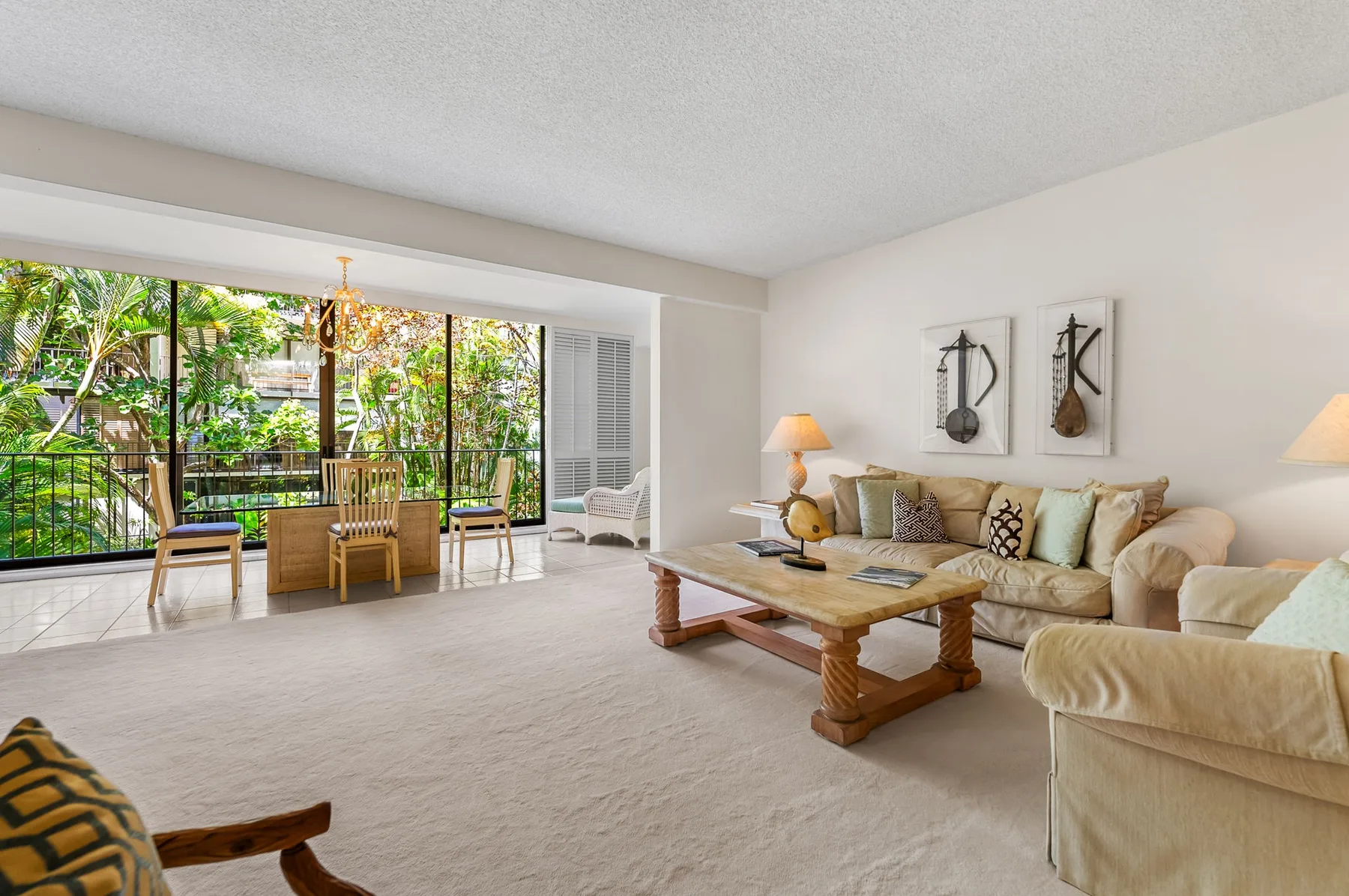 A bright living room with seating and a coffee table beside large windows.