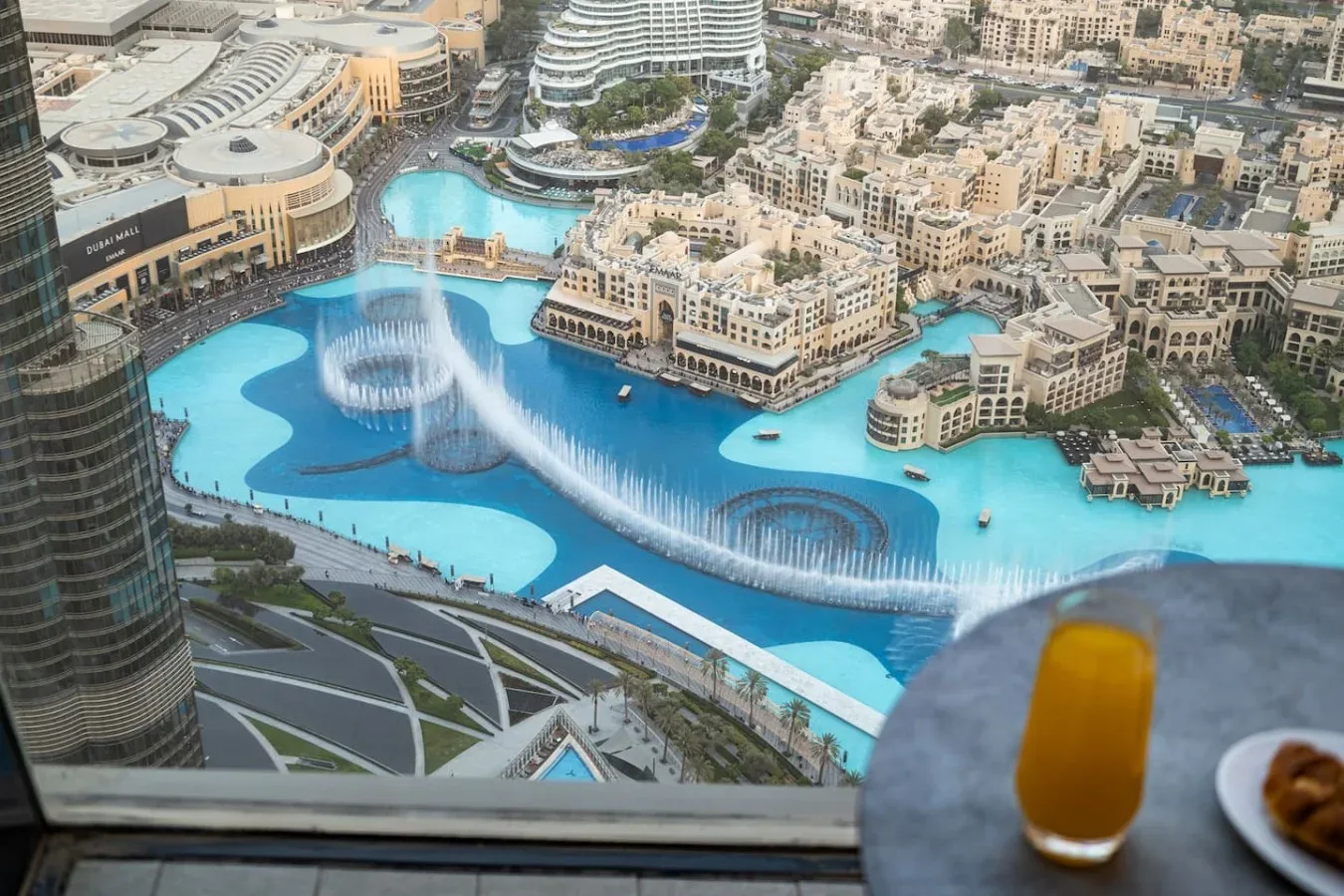 Vista aérea de una piscina turquesa y edificios circundantes, a través de una ventana.