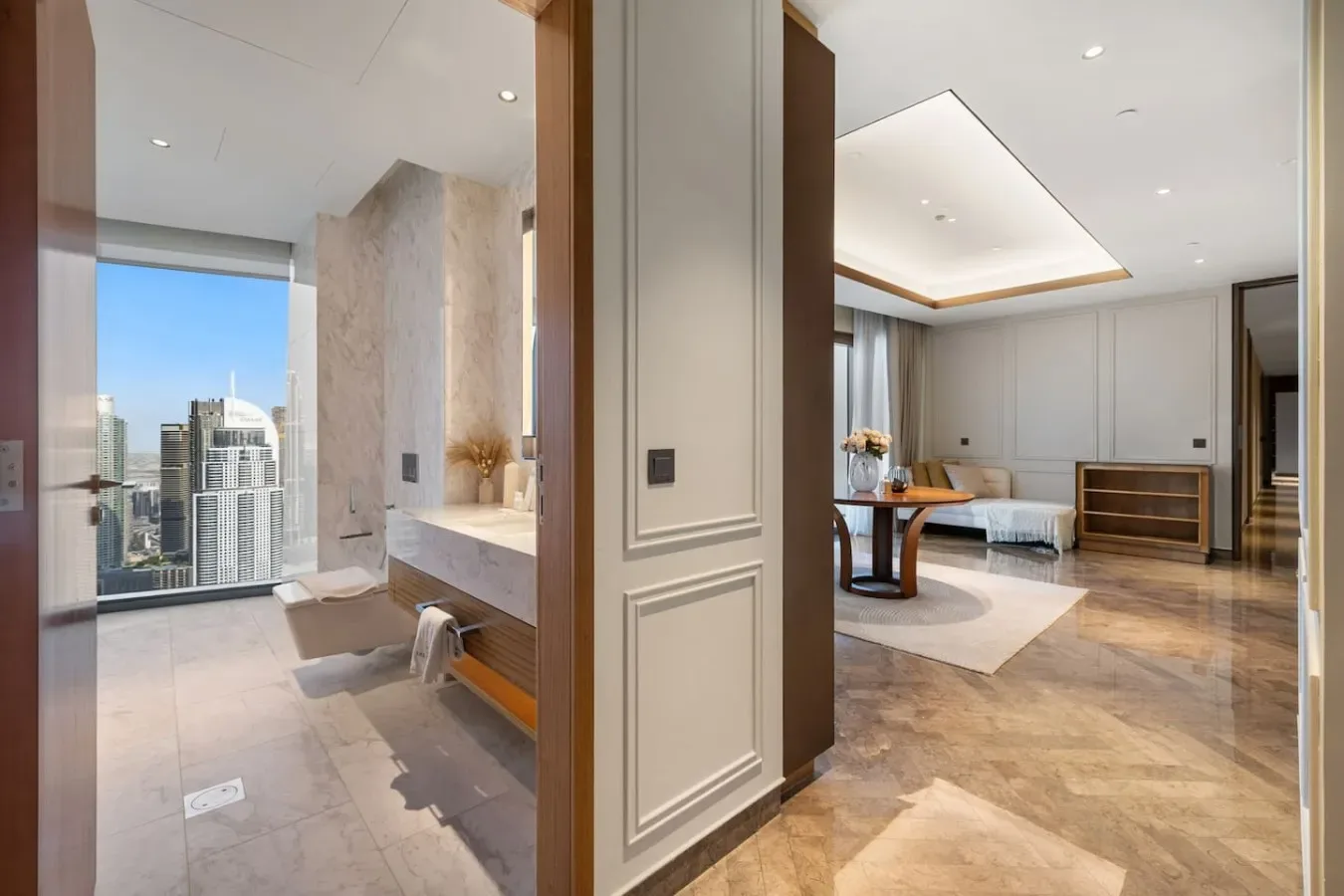 Un baño y una sala contigua con grandes ventanas y vistas a la ciudad.