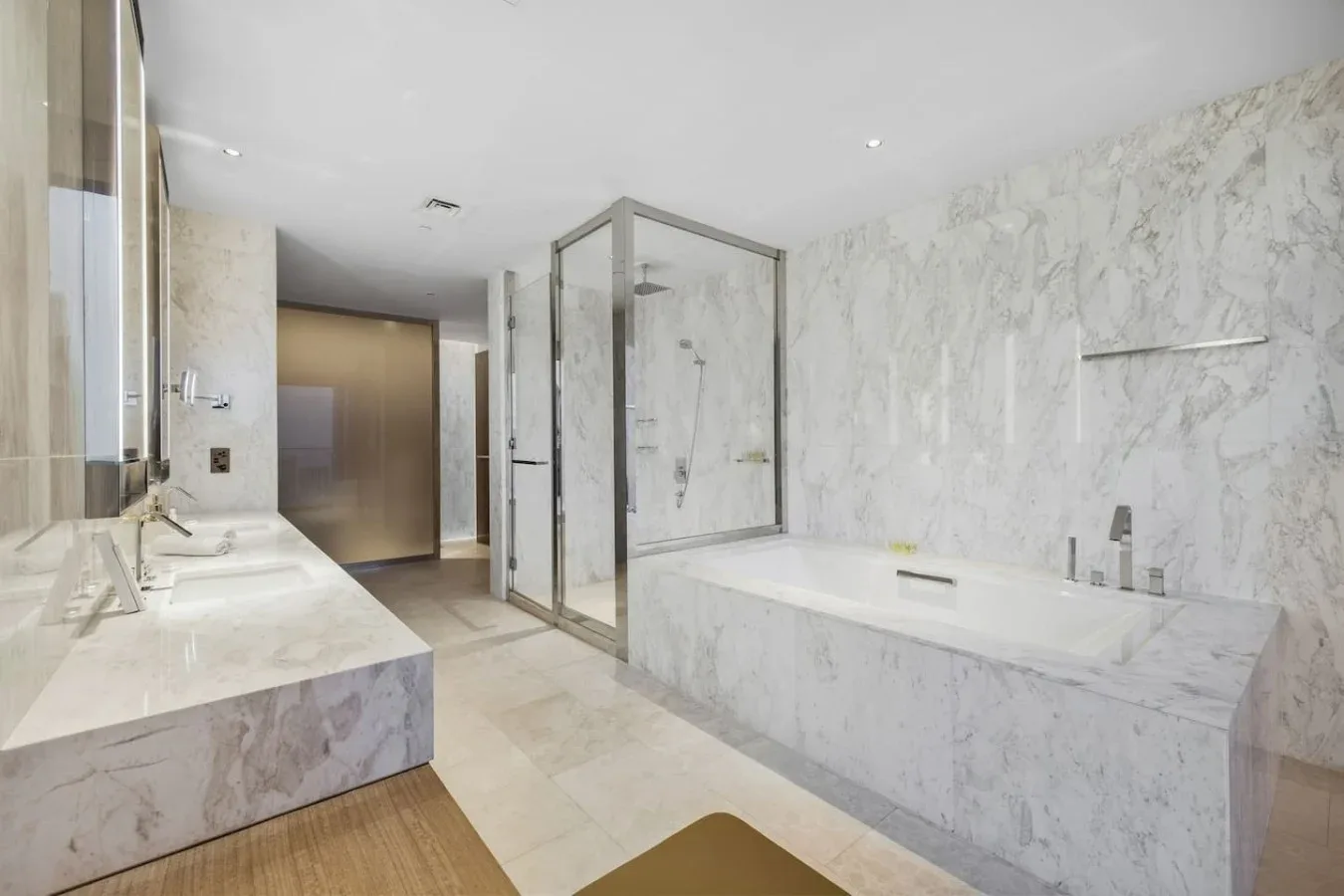 Un baño amplio con ducha de vidrio, bañera y una larga encimera con lavabo.