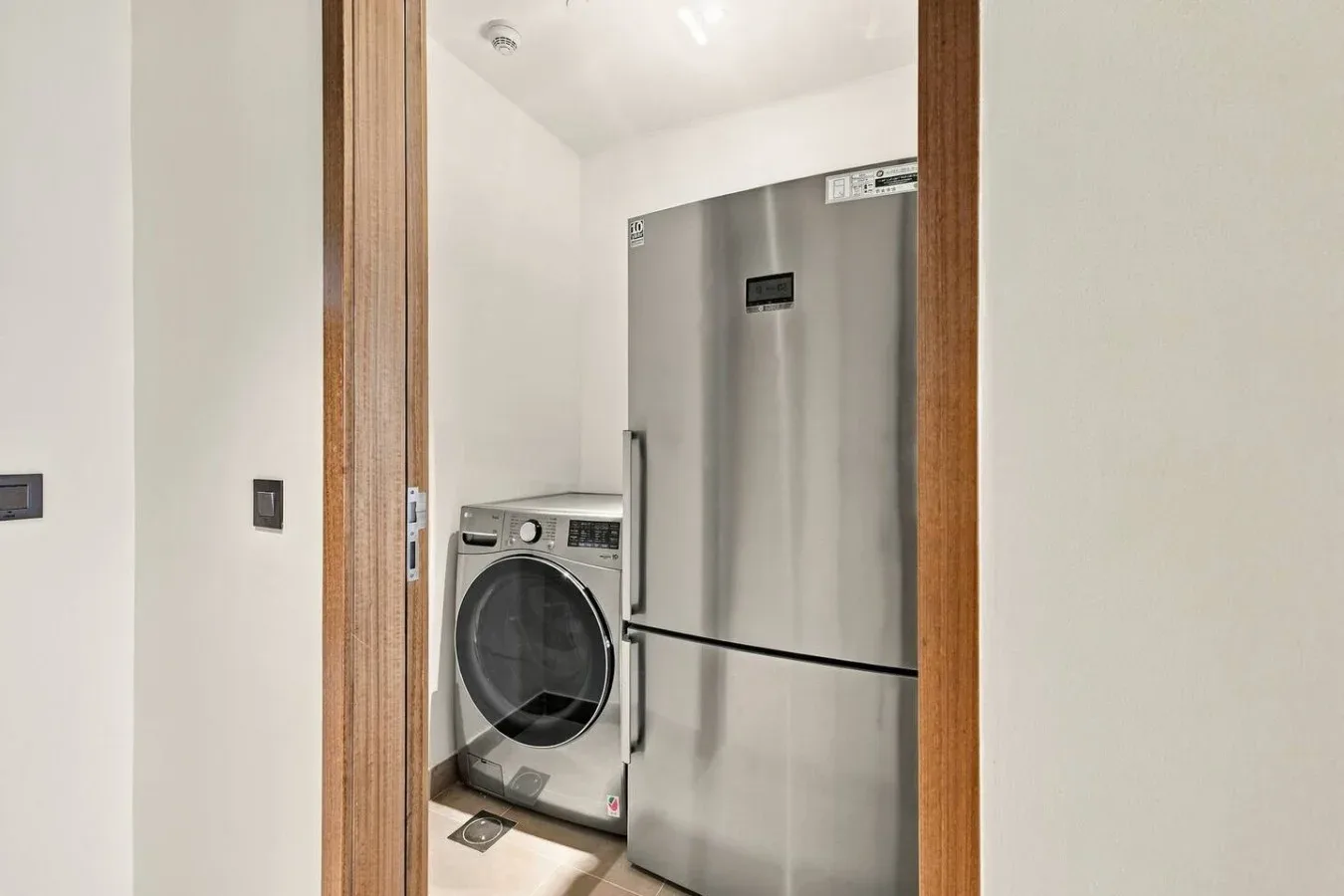 Un área de lavandería con una lavadora de carga frontal junto a un refrigerador.